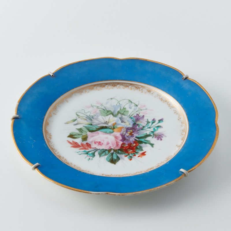 Старинная тарелка с бортом синего цвета и цветочной росписью.