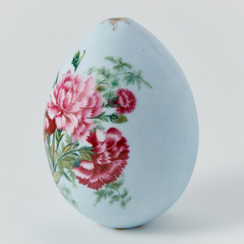 Фарфоровое пасхальное яйцо с изображением гвоздик и пионов на голубом фоне.