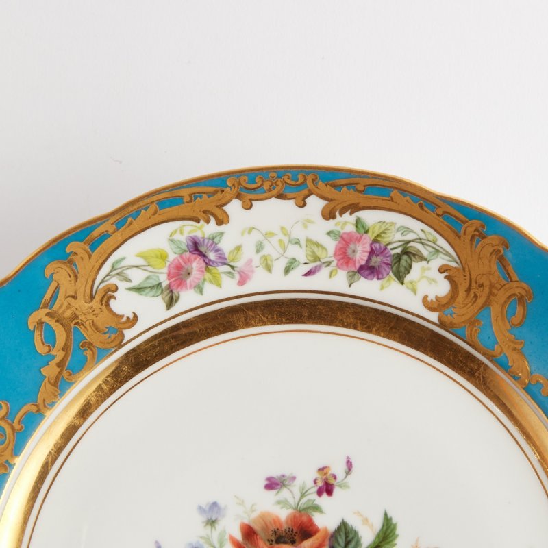 Антикварная тарелка с голубым бортом и цветочной росписью.