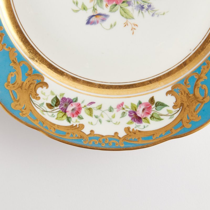 Антикварная тарелка с голубым бортом и цветочной росписью.