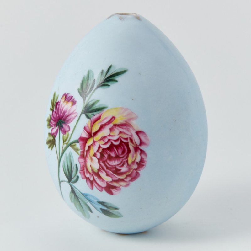 Фарфоровое пасхальное яйцо с изображением гвоздик и пионов на голубом фоне.